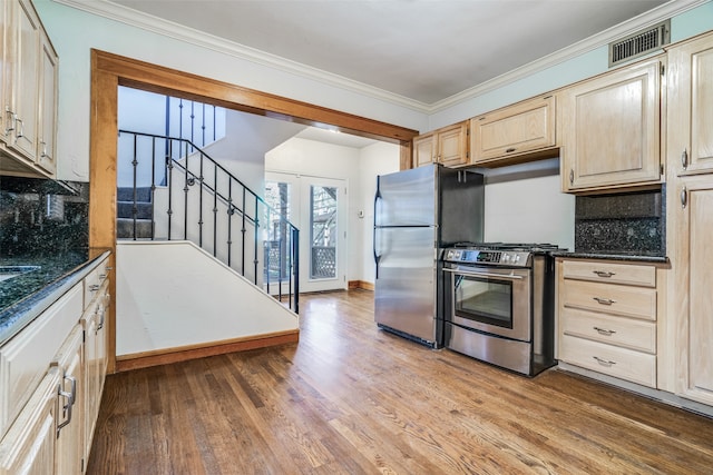 kitchen with crown molding, light wood-type flooring, backsplash, and appliances with stainless steel finishes