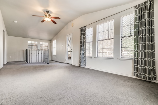 unfurnished living room with carpet flooring, vaulted ceiling, ceiling fan, and a healthy amount of sunlight