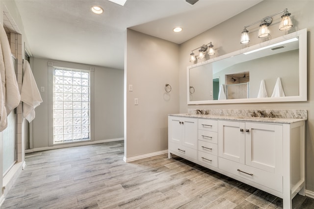 bathroom with hardwood / wood-style floors, vanity, and a shower with door