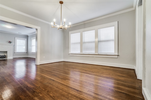 empty room with a fireplace, dark hardwood / wood-style flooring, an inviting chandelier, and ornamental molding