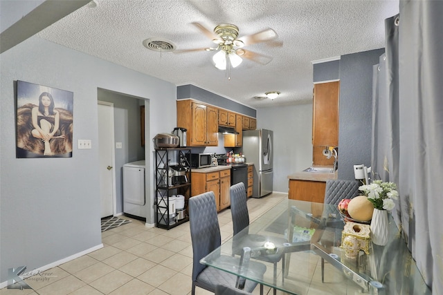 dining area featuring washer / dryer, sink, light tile patterned floors, ceiling fan, and a textured ceiling