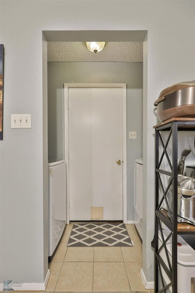 foyer with light tile patterned flooring, washer / dryer, and a textured ceiling