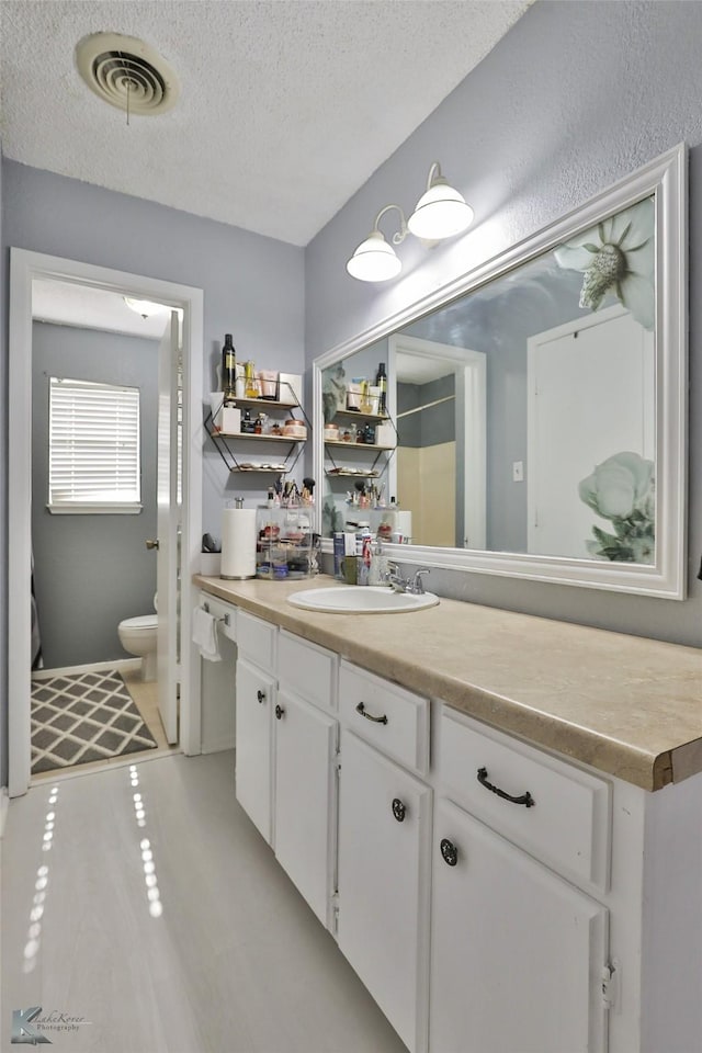 bathroom featuring vanity, a textured ceiling, and toilet