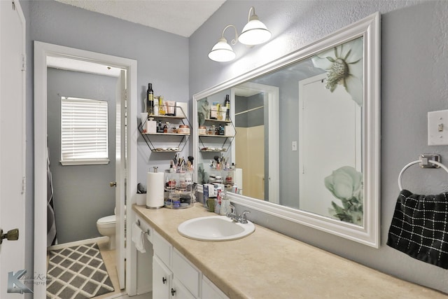 bathroom with vanity, toilet, a textured ceiling, and a shower