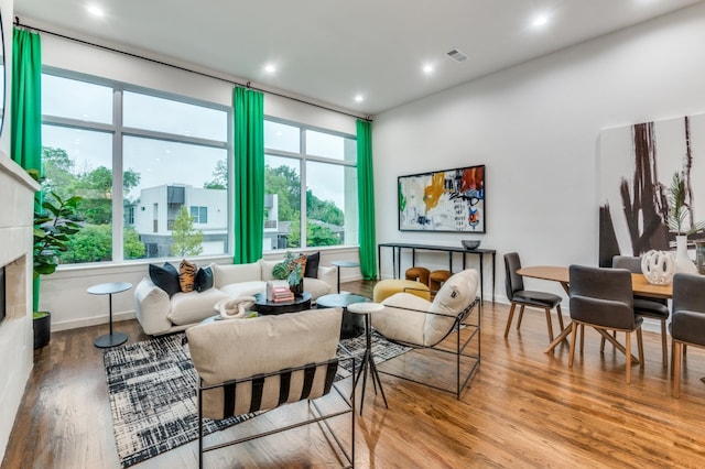 living room with a tiled fireplace and hardwood / wood-style floors