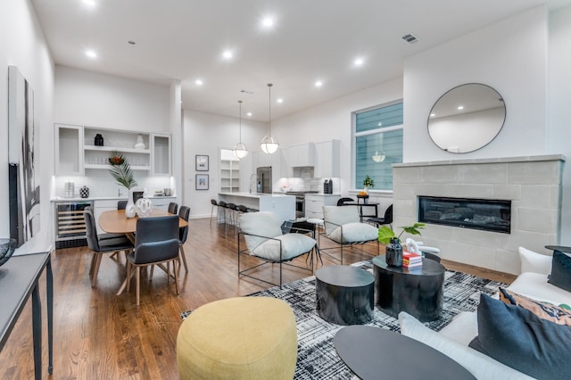 living room with a tile fireplace, wine cooler, and wood-type flooring