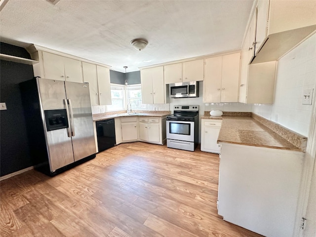 kitchen with hanging light fixtures, light wood-type flooring, stainless steel appliances, and light countertops