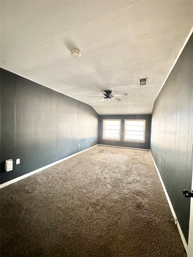 unfurnished room featuring ceiling fan, carpet flooring, and wooden walls