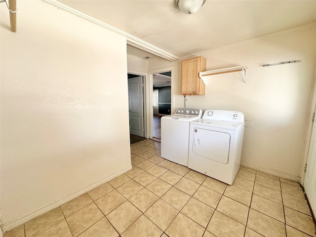 clothes washing area featuring cabinets, light tile patterned flooring, and washer and dryer