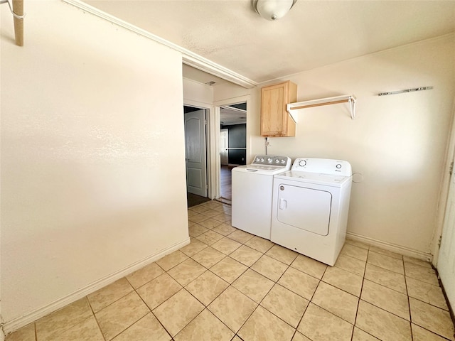 clothes washing area with washer and dryer, cabinet space, baseboards, and light tile patterned flooring