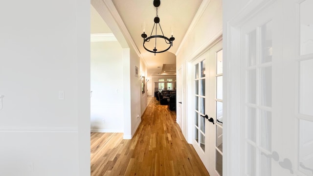 hall with crown molding, hardwood / wood-style floors, a chandelier, and french doors