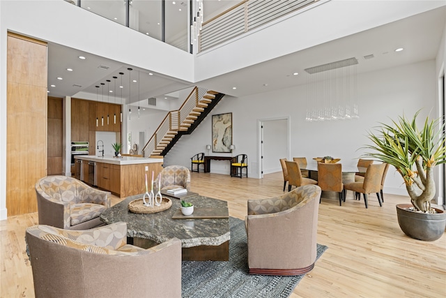 living room with light wood-type flooring and a towering ceiling