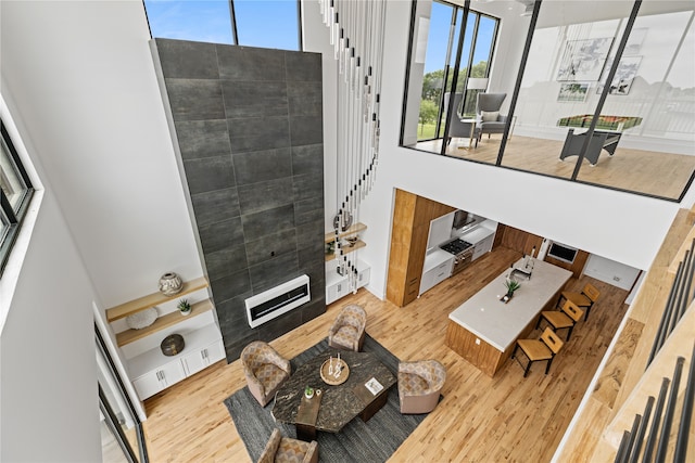 living room with a towering ceiling, a tile fireplace, and light hardwood / wood-style floors