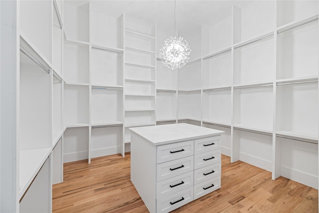 spacious closet with light wood-type flooring and an inviting chandelier