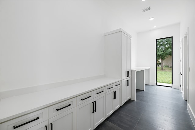 hall with dark tile patterned flooring and a wealth of natural light