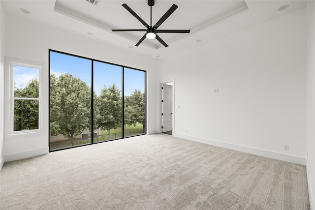 carpeted empty room with ceiling fan and a tray ceiling