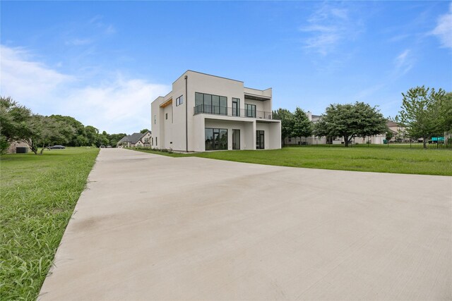 modern home with a front lawn and a balcony