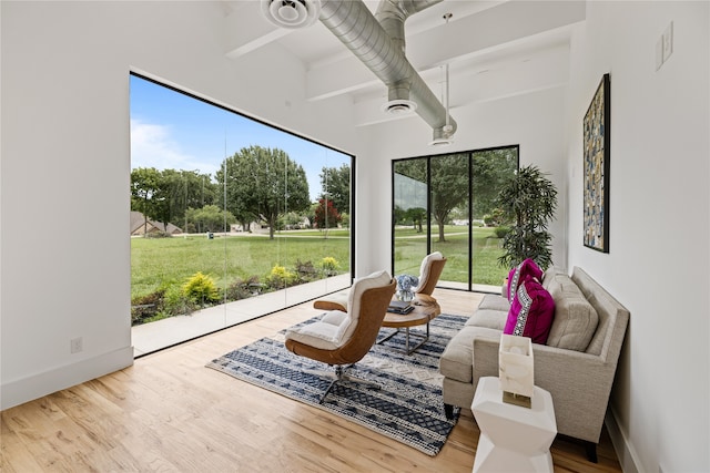 sitting room with light hardwood / wood-style flooring, plenty of natural light, and beamed ceiling