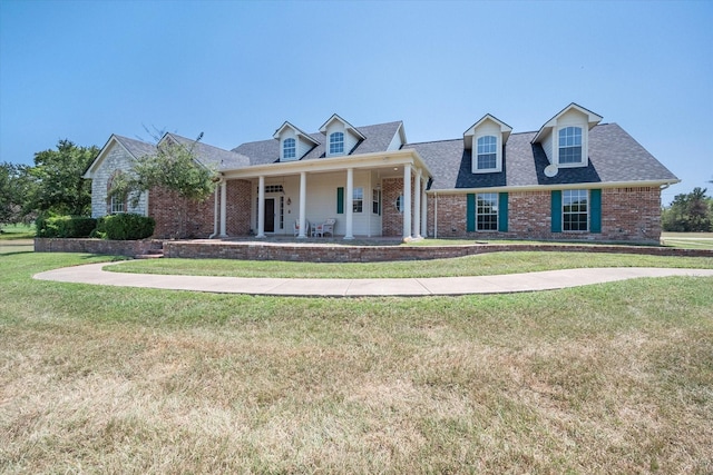 cape cod home with covered porch, roof with shingles, brick siding, and a front lawn