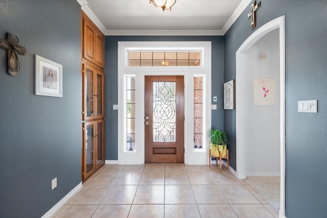 foyer featuring baseboards, arched walkways, crown molding, and light tile patterned flooring