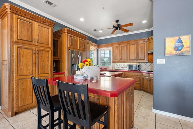 kitchen featuring light tile patterned floors, a kitchen island, visible vents, ornamental molding, and stainless steel fridge with ice dispenser