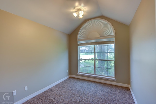 carpeted spare room featuring baseboards and vaulted ceiling