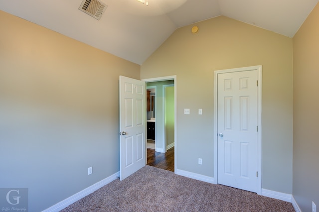 unfurnished bedroom featuring vaulted ceiling and carpet floors