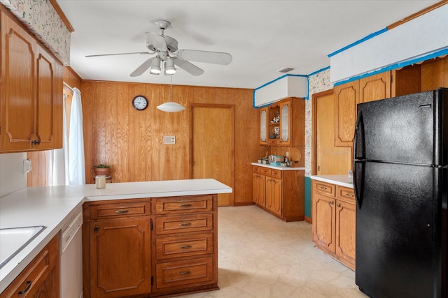 kitchen with white dishwasher, black fridge, ceiling fan, and wood walls