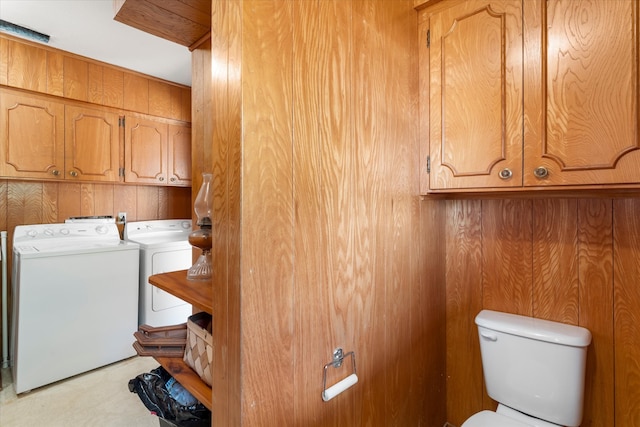 laundry room with wood walls, cabinets, and washer and dryer