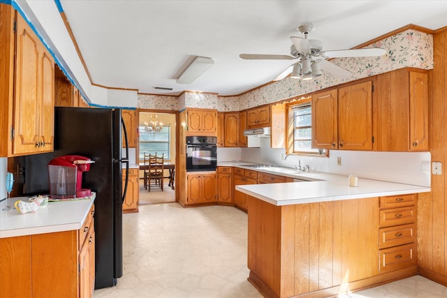 kitchen with black appliances, ceiling fan with notable chandelier, kitchen peninsula, and sink