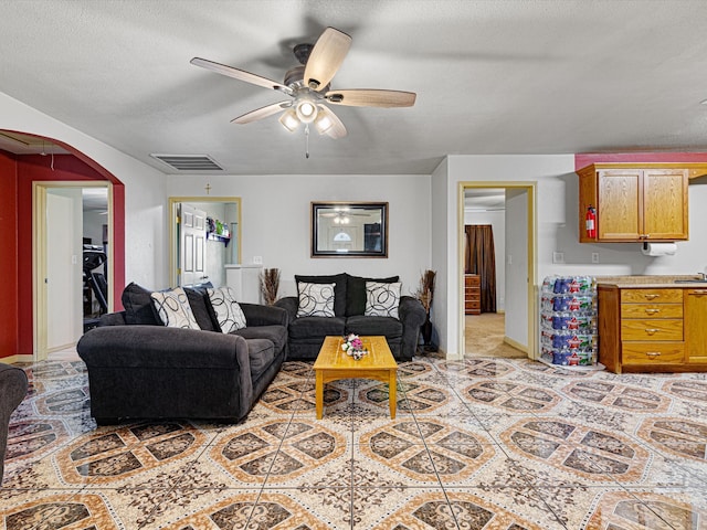 carpeted living room featuring ceiling fan and a textured ceiling