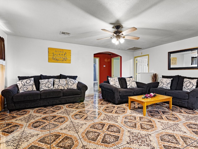 living room with ceiling fan and a textured ceiling