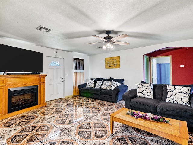 living room with tile patterned floors, ceiling fan, and a textured ceiling