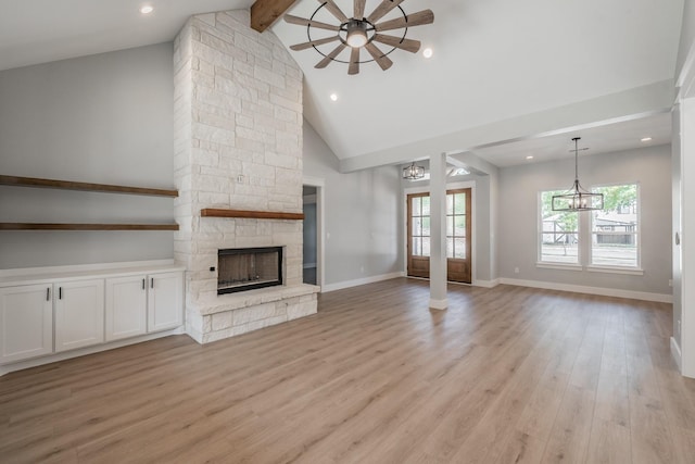 unfurnished living room with light wood finished floors, baseboards, a stone fireplace, high vaulted ceiling, and beam ceiling