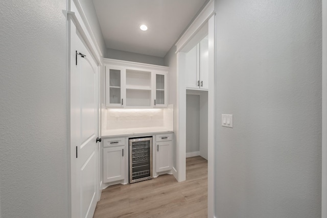 bar with a dry bar, recessed lighting, a textured wall, light wood-type flooring, and beverage cooler