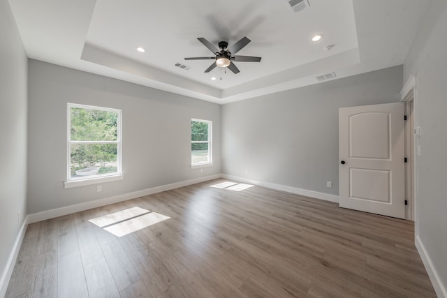 spare room featuring ceiling fan, a tray ceiling, and wood-type flooring