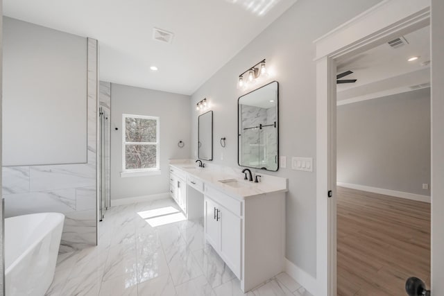 bathroom featuring double vanity, marble finish floor, a freestanding tub, and a sink