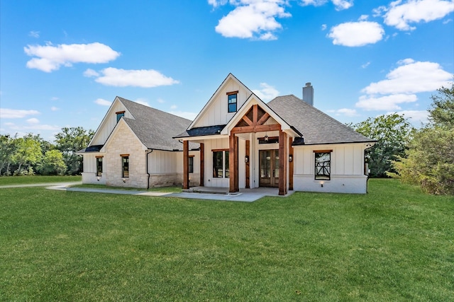 view of front facade featuring board and batten siding, a front yard, a shingled roof, and a chimney