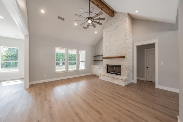 unfurnished living room with light wood-style floors, visible vents, plenty of natural light, and a stone fireplace