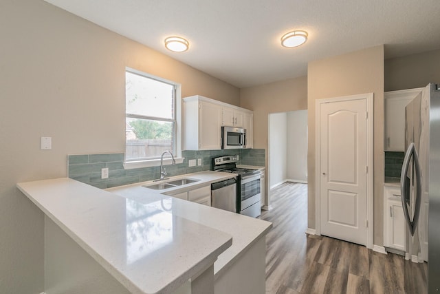 kitchen with a peninsula, white cabinets, stainless steel appliances, and light countertops