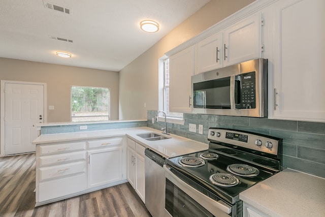 kitchen featuring stainless steel appliances, light hardwood / wood-style floors, kitchen peninsula, and white cabinetry