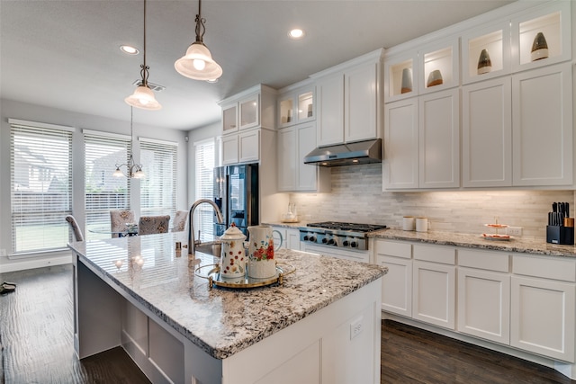 kitchen featuring decorative backsplash, white cabinets, and a kitchen island with sink