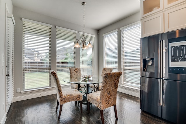 dining space with dark hardwood / wood-style flooring, a wealth of natural light, and an inviting chandelier