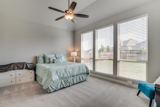 carpeted bedroom featuring lofted ceiling, ceiling fan, and multiple windows