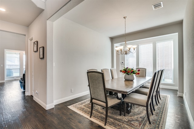 dining room with dark hardwood / wood-style floors and an inviting chandelier