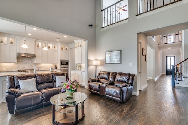 living room featuring dark wood-type flooring and a towering ceiling