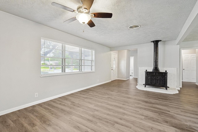 2120 Nottingham Blvd, Fort Worth, TX 76112 - unfurnished living room with hardwood / wood-style flooring, a wood stove, and a textured ceiling