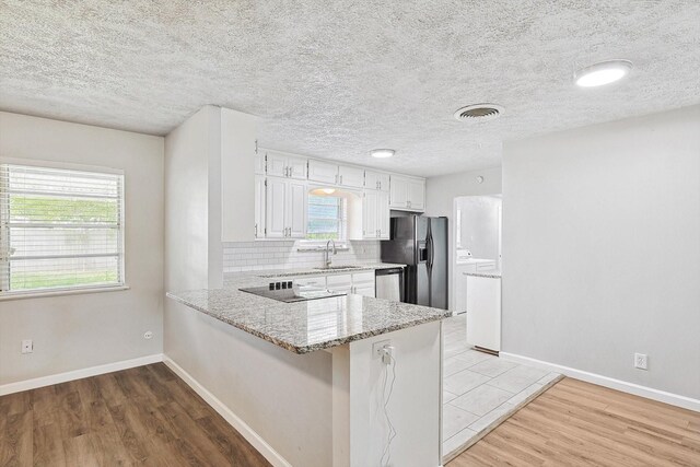 2120 Nottingham Blvd, Fort Worth, TX 76112 - kitchen with tasteful backsplash, white cabinetry, black appliances, sink, and kitchen peninsula