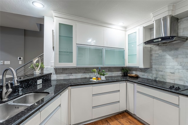 kitchen with backsplash, sink, wall chimney range hood, and white cabinets