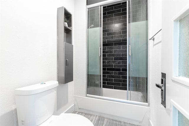 bathroom with bath / shower combo with glass door and toilet